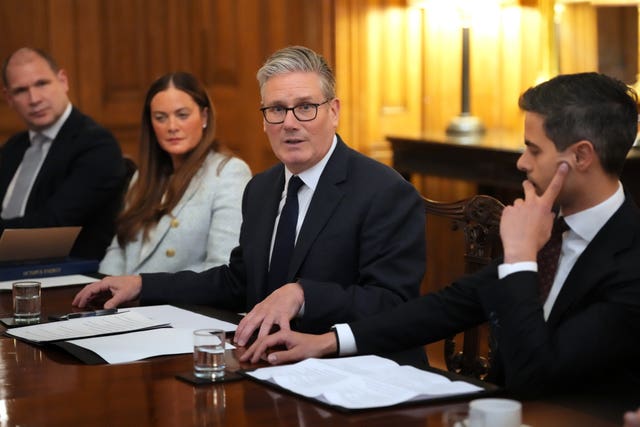 Sir Keir Starmer speaking while seated at a long wooden table