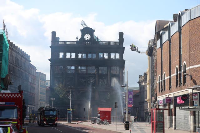 Fire hoses spray water to dampen burning embers inside the Primark store in Belfast