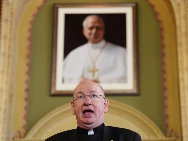 Bishop Richard Moth speaking in front of a portrait of Pope Leo XIV in the background