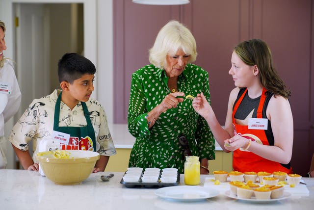 Camilla helps two children make cupcakes 
