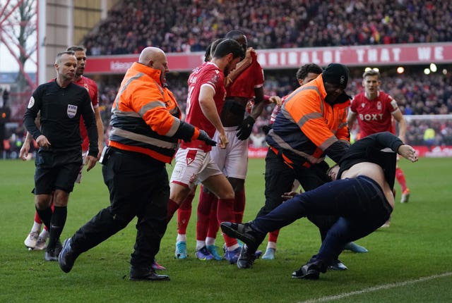 A Leicester fan is dragged away by stewards from celebrating Nottingham Forest players