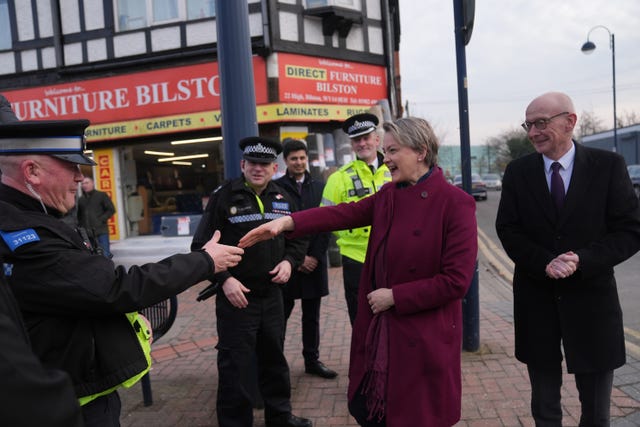 Home Secretary Yvette Cooper reaches out to shake hands with a police officer 