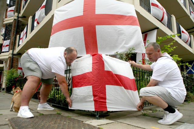 Chris Dowse (left) and Alan Putman, secure a flag on the Kirby Estate in Bermondsey, south London (Luciana Guerra/AP)