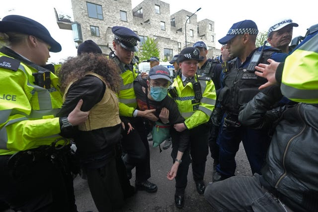 Police remove a protester after demonstrators formed a blockade around the coach