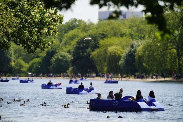 People ride pedalo and rowing boats in the hot weather on the Serpentine in Hyde Park, in London