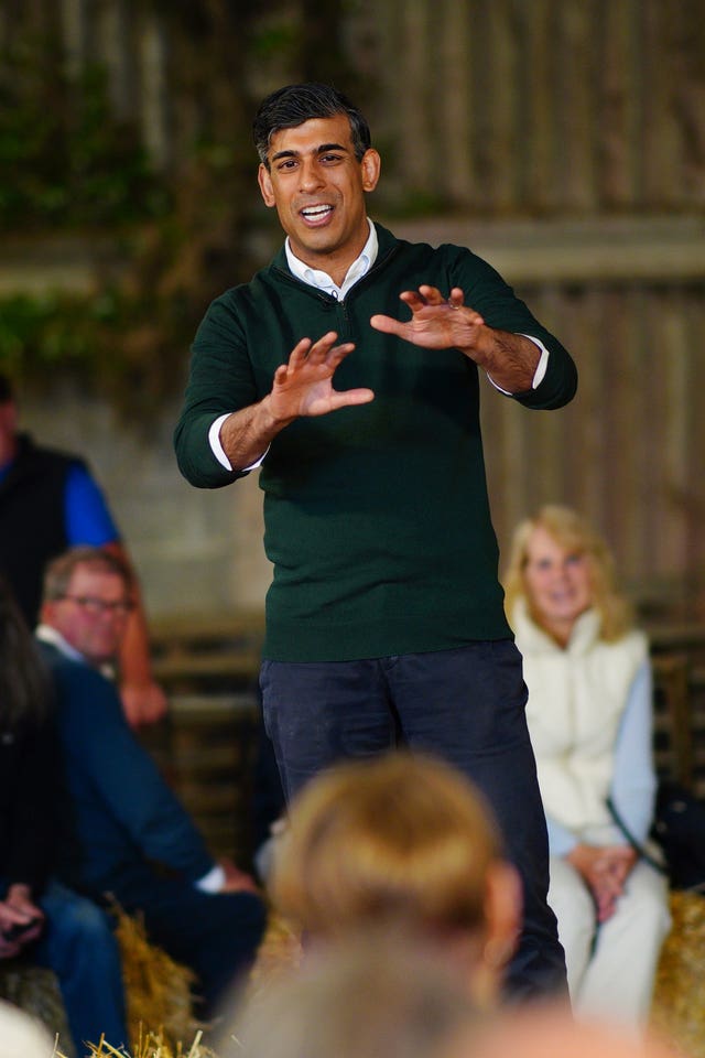 Prime Minister Rishi Sunak standing up talking to a group of people