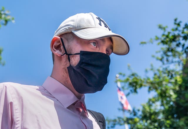 Josh Greally leaves court wearing a cap and face mask