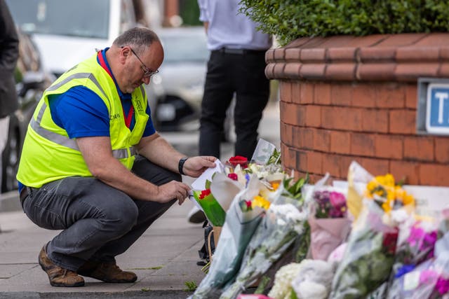 Man laying flowers at a memorial for those hurt and killed in Southport