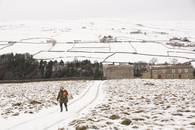 A woman walks through the snow in the fields