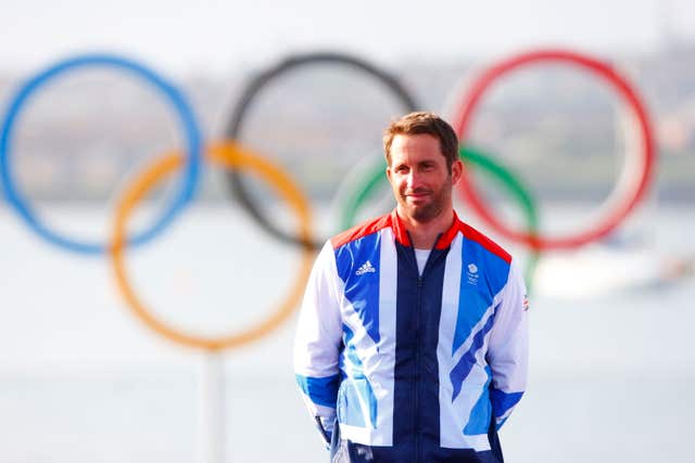 Sir Ben Ainslie stands in front of the Olympic rings 