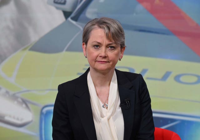 Yvette Cooper in front of a screen showing a police vehicle