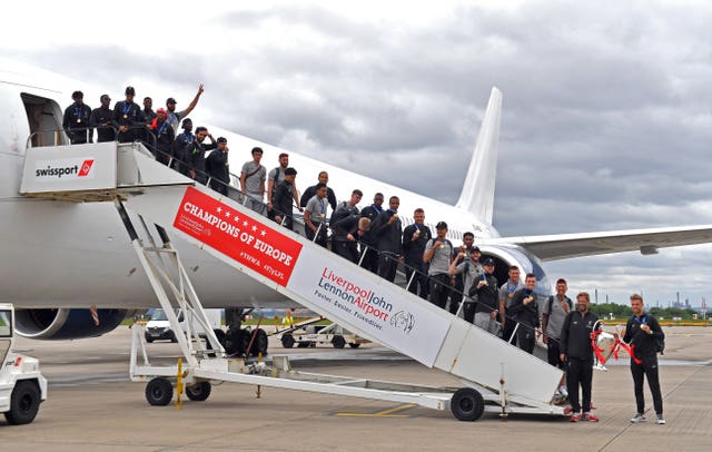 The Liverpool team pose for a photo with the trophy on the steps of the plane