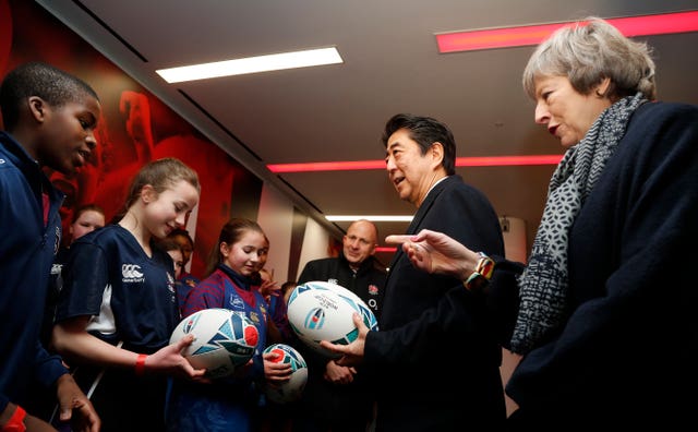 Mrs May and Mr Abe chatting to school children at the stadium