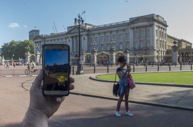 People playing the Pokemon Go reality game on their phone outside Buckingham Palace in London.
