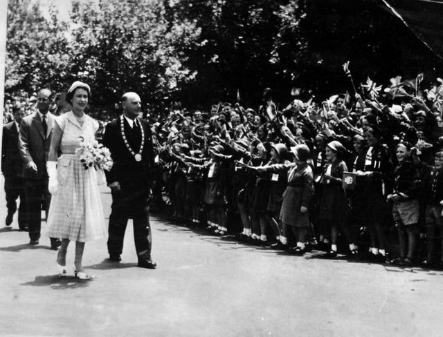 The Queen, followed by the Duke of Edinburgh, and walking beside the mayor of Cambridge, Dr. HC Tod, visits Boy Scouts and Girl Guides in Cambridge, New Zealand, in 1954 