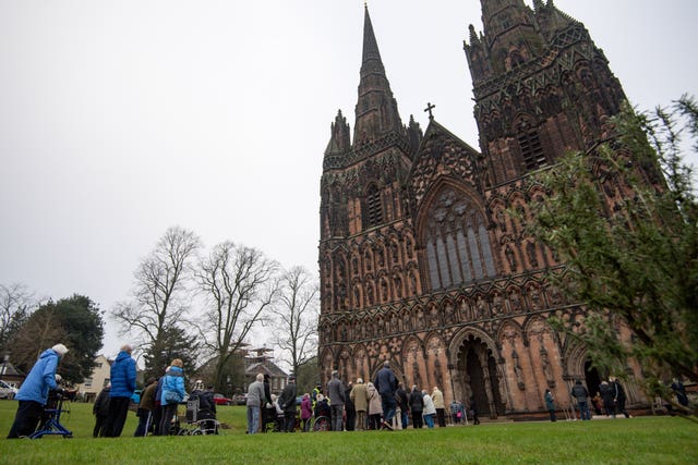 Members of the public queue outside Lichfield Cathedral, Staffordshire, to receive an injection of the Oxford/AstraZeneca coronavirus vaccine (Jacob King/AP)