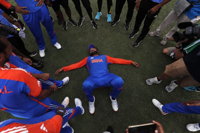 India's Rohit Sharma lays on his back with team-mates standing in a circle around him