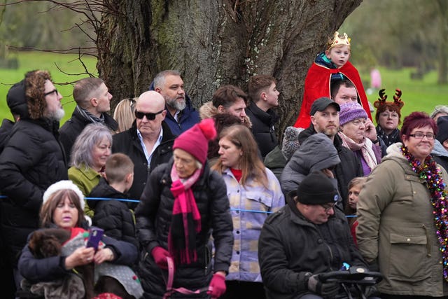 A young boy dressed in a crown with members of the public gathered ahead of the Christmas Day morning church service attended by the royal family at St Mary Magdalene Church in Sandringham 