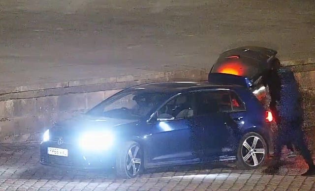 CCTV screengrab showing men loading an object into the boot of a car