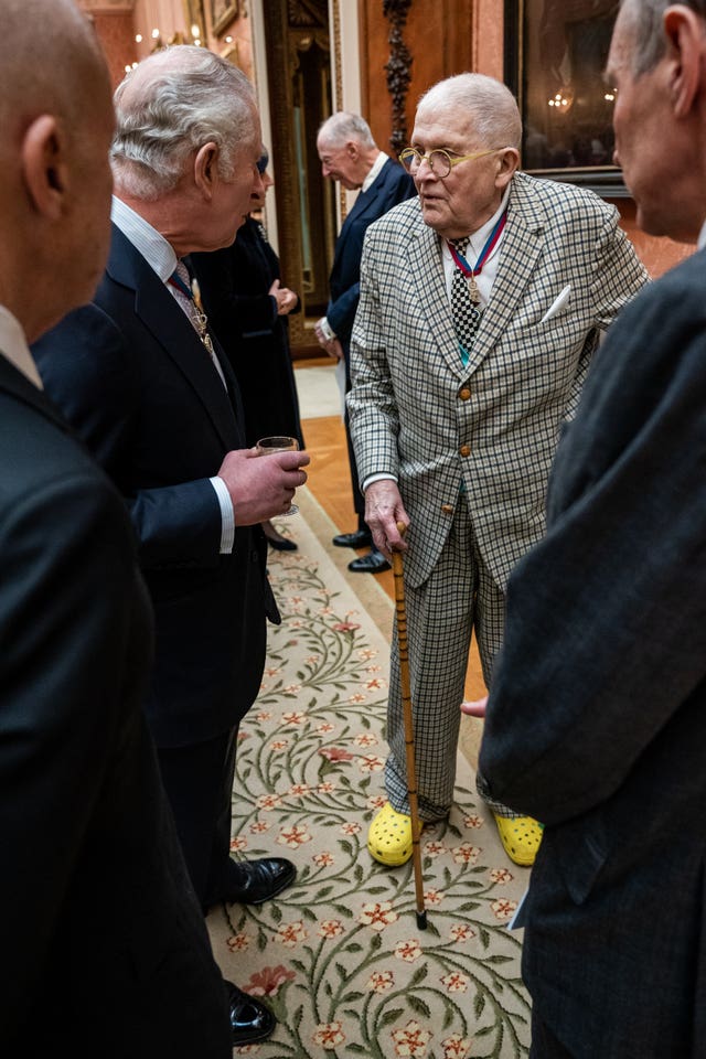 The King talks to David Hockney during a luncheon for Members of the Order of Merit at Buckingham Palace, where the artist wore bright yellow shoes 