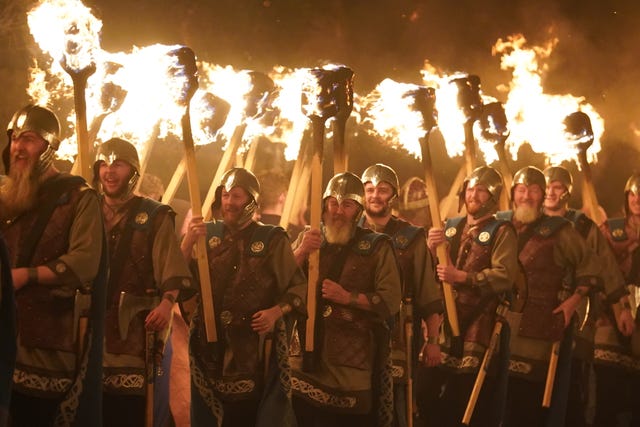 Revellers dressed in Norse costumes holding flaming torches