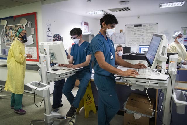 Staff members work at a desk in the ICU