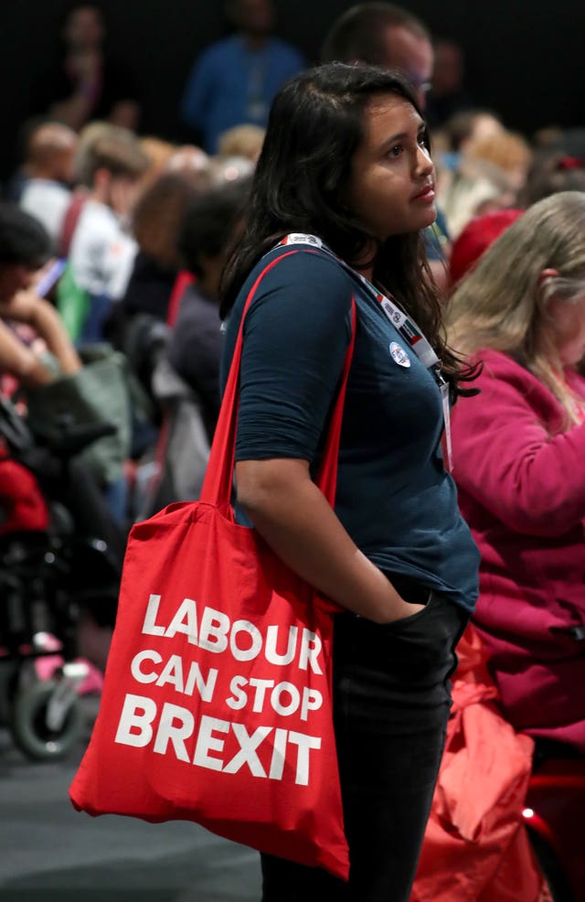 A woman in the Labour Party Conference hall looking dejected and carrying a bag that says 'Labour can stop Brexit'