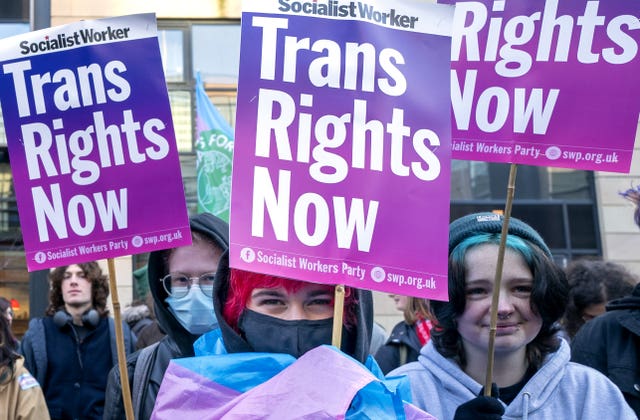 Campaigners holding up signs reading 'Trans rights now'