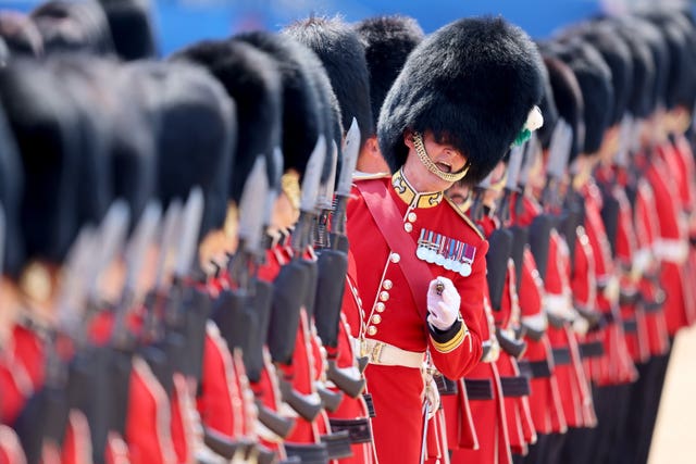 Soldiers lined up in red uniforms and bearskin hats