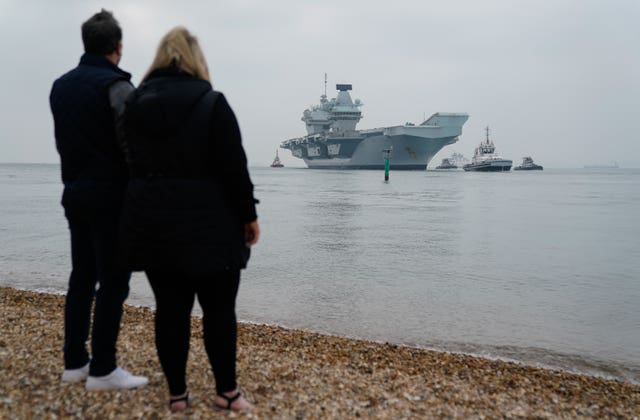 People look on as the Royal Navy aircraft carrier HMS Queen Elizabeth arrives back in Portsmouth harbour