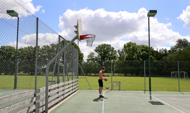 A basketball player trains himself on an empty multi-sport court