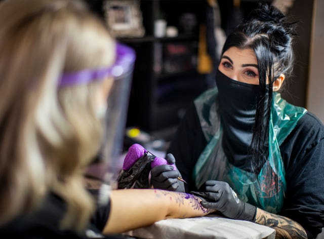 Tattoo artist Kirsty Mick (right) tattooing customer Chloe McEnhill at Belfast City Skinworks, as tattoo parlours in Northern Ireland are allowed to reopen as lockdown eases