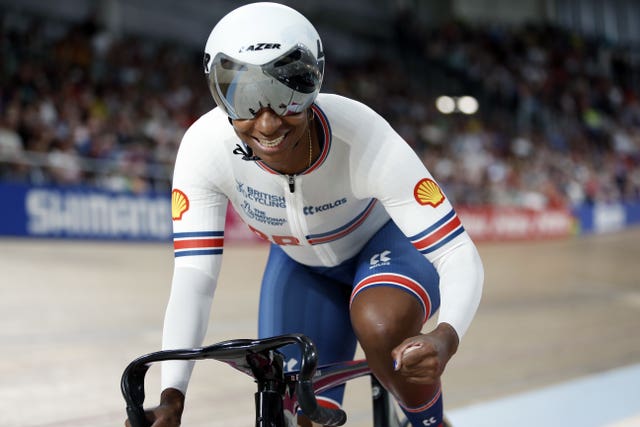 Kadeena Cox smiles and clenches her fist in celebration while riding her bike