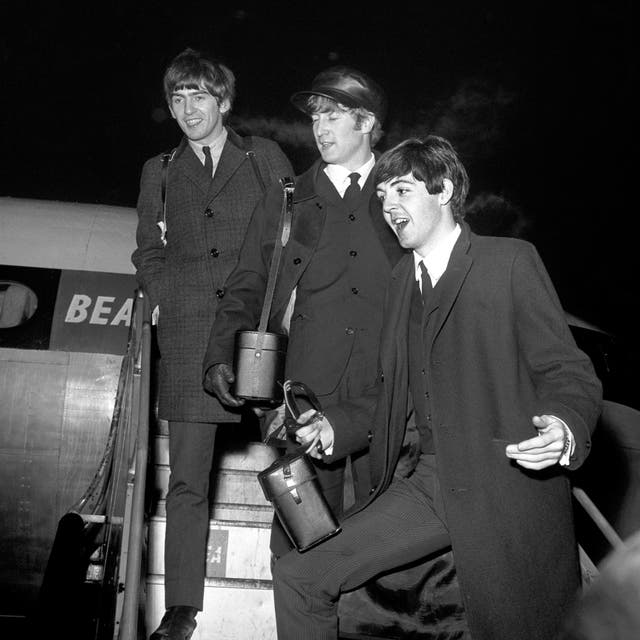  Black and white photo of George Harrison, John Lennon and Paul McCartney on stairs leading up to a plane