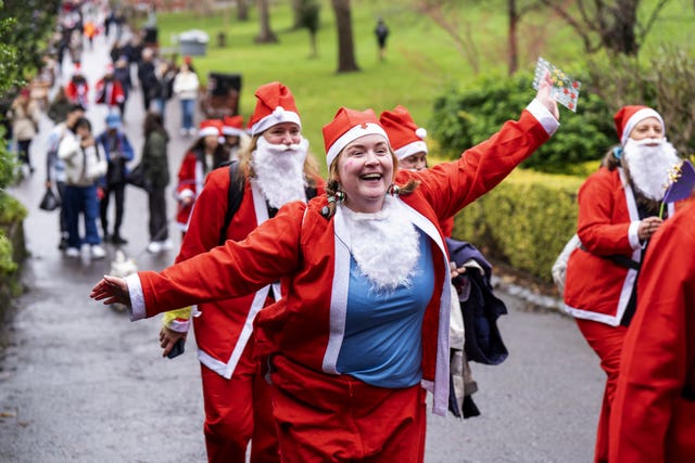 A woman smiles with her arms outstretched at the Edinburgh Santa Dash