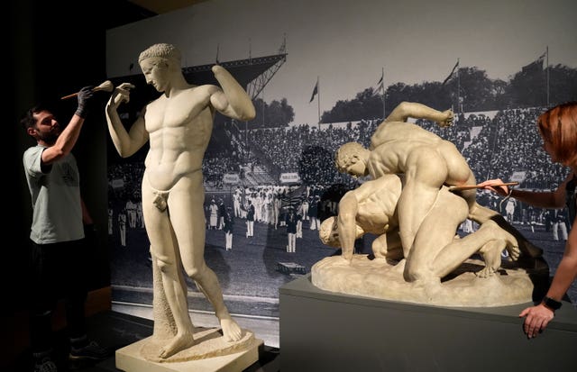 Technicians dust a work which is on display at the Paris 1924: Sport, Art and the Body exhibition