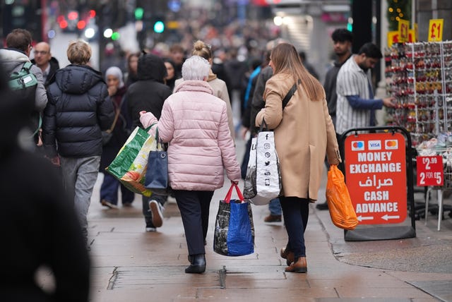 Shoppers carrying bags walk down a high street