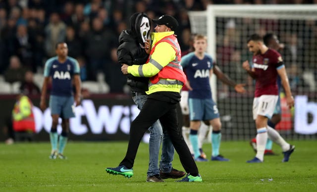 A pitch invader wearing a scream mask is taken off the pitch at the London Stadium. (PA)