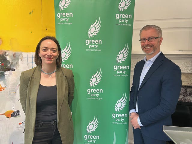 Janet Horner and Roderic O'Gorman posing for a photo in front of Green Party signage