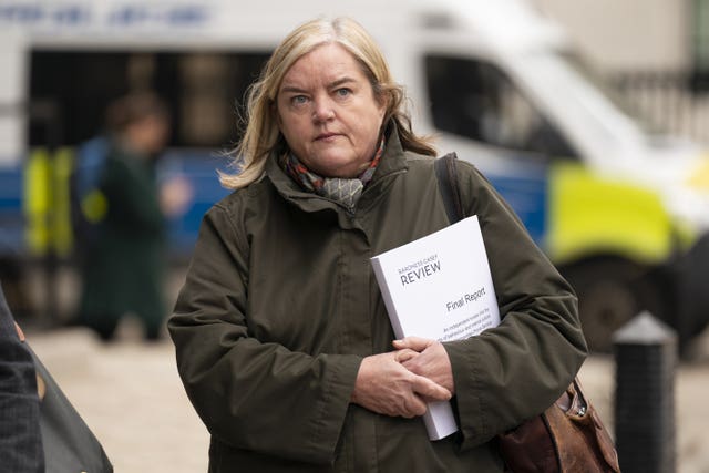 Baroness Casey wearing a green jacket and holding a copy of her review in the crook of her arm.