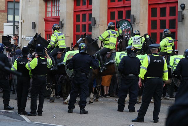 Police horses hold back people outside Bridewell police station 