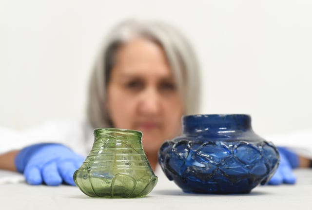 Conservator Claire Reed inspects decorated glass beakers found at the site 