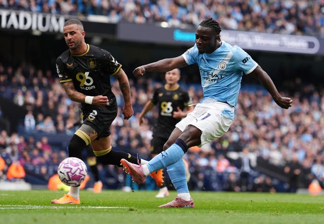 Jeremy Doku (right) shoots under pressure from Kyle Walker (left).