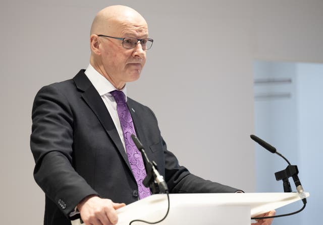 John Swinney standing at a lectern