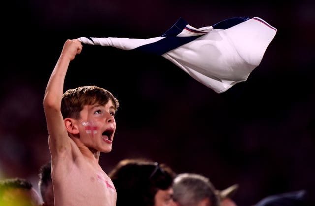 A young England fan waves his England shirt above his head