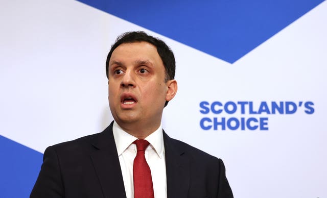 Anas Sarwar speaking in front of a large Scottish flags which features the words 'Scotland's choice'