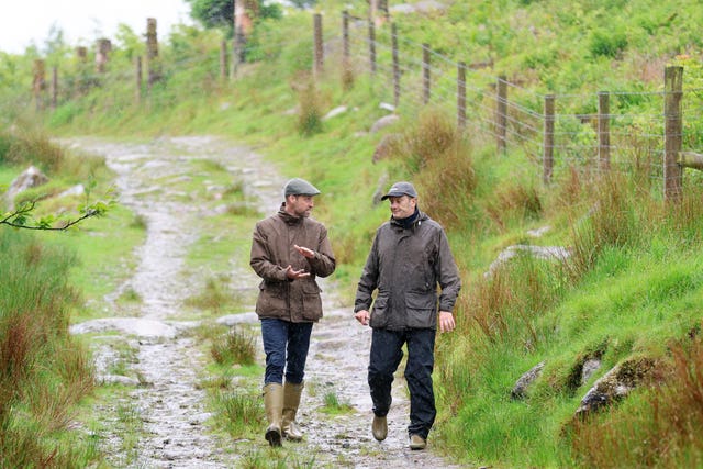 William, wearing a flat cap and wellies, talking to another man on Dartmoor