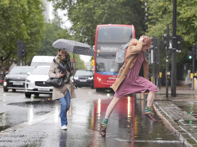 A woman jumps over a puddle on Euston Road in London