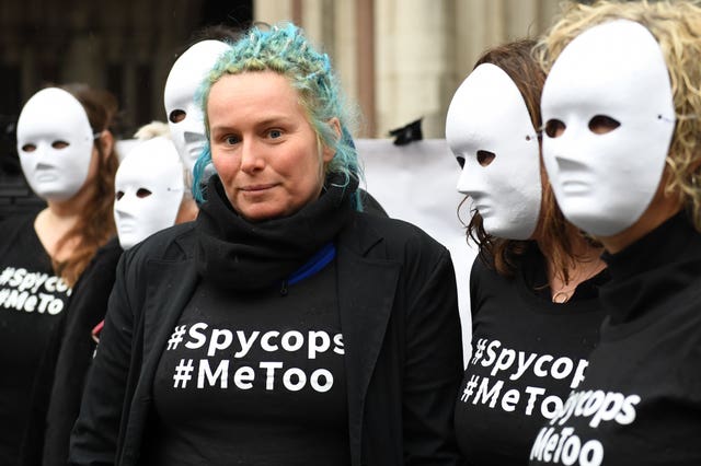 Kate Wilson flanked by supporters wearing blank, white masks.