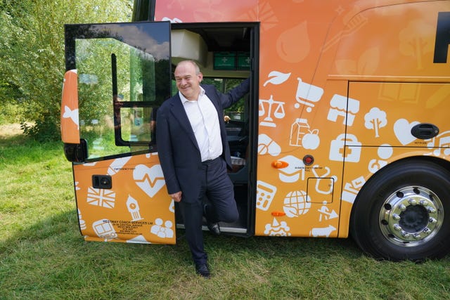 Sir Ed Davey smiles at the door of the orange Liberal Democrat battlebus